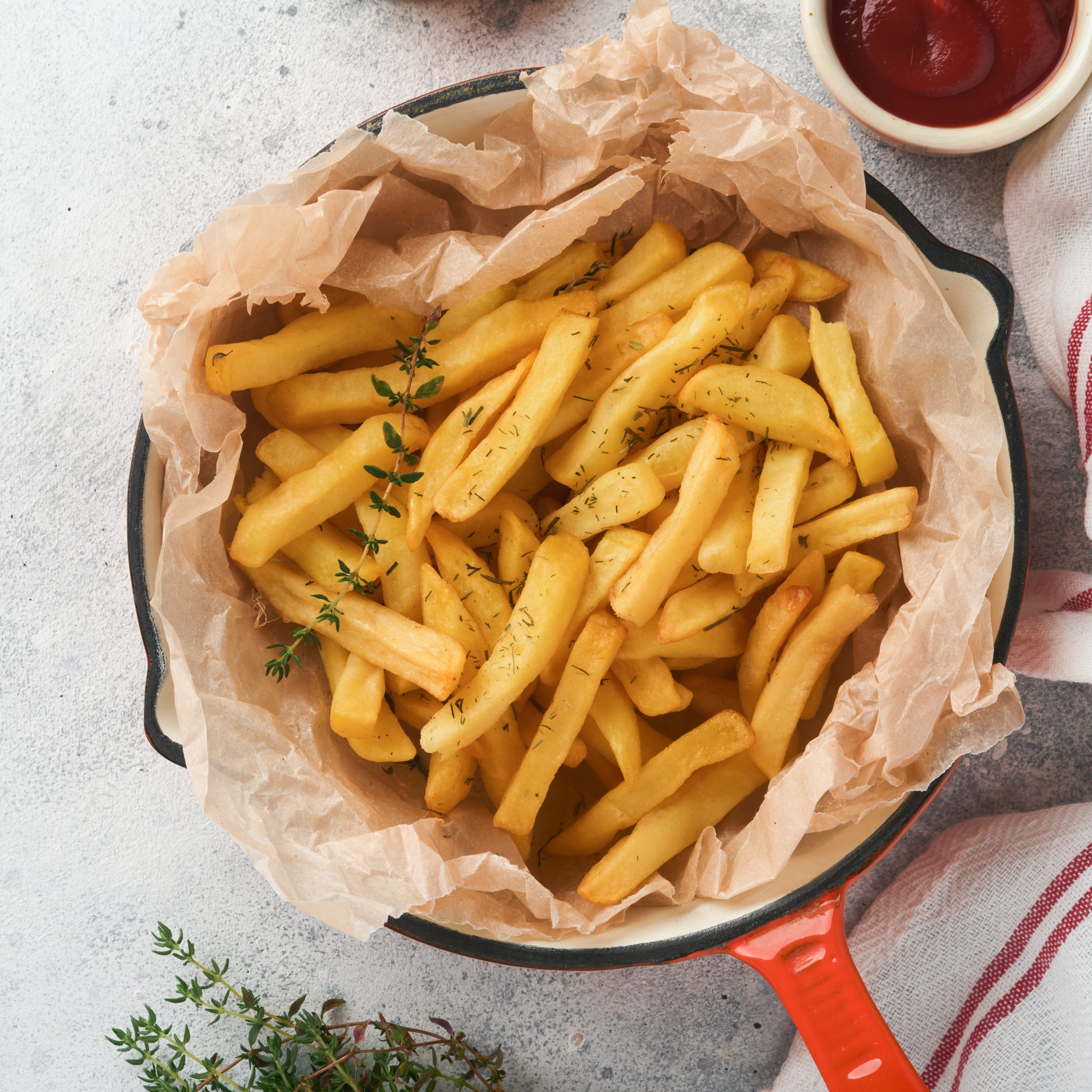 French fries. Tasty French fries server in red cast iron skillet with tomato and cheese sauce on old gray concretetable background. Diverse Keto Dishes. Fast food and unhealthy food concept. Картопля Фрі McCAIN Caterpak Заморожена Ярофрут 6х6