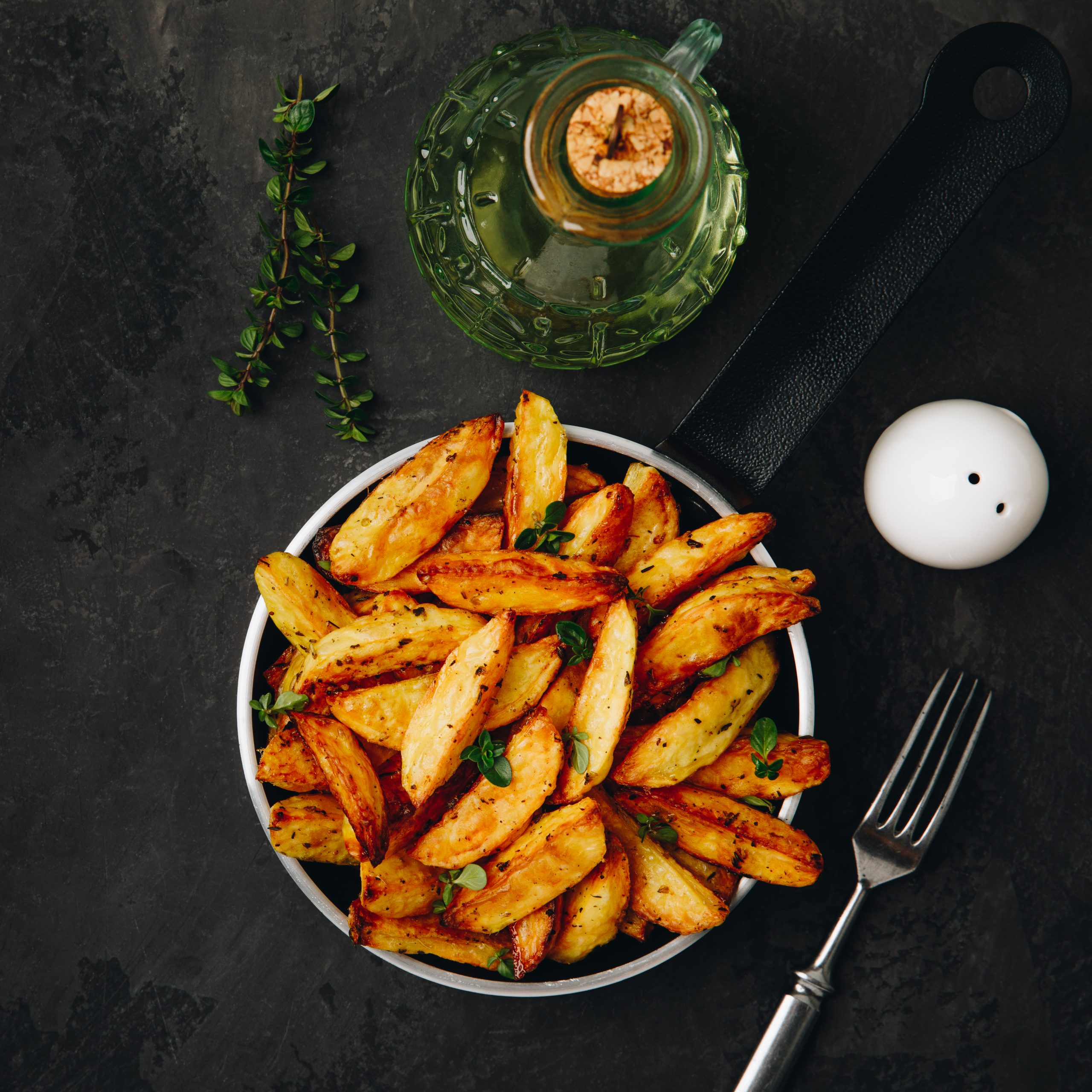 Roasted potatoes. Baked potato wedges in frying pan on dark ston Картопляні Скибки Kipco Damaco Заморожені Ярофрут Клас А